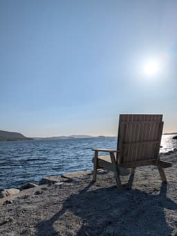 Homemade wooden lounger chair on the deck, right by the water